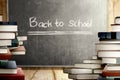 Close up view of pile of books on wooden table and blackboard with Back to School message Royalty Free Stock Photo