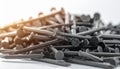 Pile of dark metal construction nails with textured heads and sharp points on a white surface Royalty Free Stock Photo