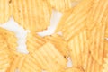 Close-up view of a pile of yellow ruffled potato chips on a white surface, brightly lit without harsh shadows. Royalty Free Stock Photo