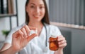 Close up view of pill that is in the hand. Young beautiful female doctor in white coat is in the office Royalty Free Stock Photo