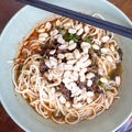 Close up view of plate with Sichuan style noodles like spicy noodle with chicken gizzard, minced, vegetables and peanut, China