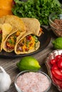 Close-up view of plate with tasty mexican tacos on rustic wooden table with ingredients for cooking background. Concept of Royalty Free Stock Photo