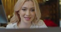 Close-up view of a pleased positive young woman is using her silver laptop computer while sitting in the white cozy cafe Royalty Free Stock Photo