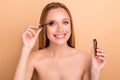 Close-up view portrait of nice attractive lovely shine cheerful glad nude naked girl applying new product brush tube