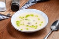 Close up view on potato cream soup with mitboli with pesto served on grey plate on brown wooden table. Modern chef cuisine. Copy