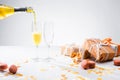 close up view of pouring yellow champagne into glasses process, macarons and arranged gifts