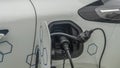 Close-up view of power supply plugged into an electric car being charged. White electric car charging Royalty Free Stock Photo