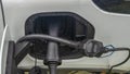 Close-up view of power supply plugged into an electric car being charged. White electric car charging. Royalty Free Stock Photo