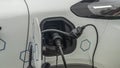 Close-up view of power supply plugged into an electric car being charged. White electric car charging. Royalty Free Stock Photo