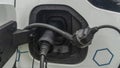 Close-up view of power supply plugged into an electric car being charged. White electric car charging Royalty Free Stock Photo