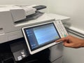 Close up view of a printer with a male hand point to the touch screen