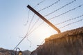 Close-up view prison or border concrete wethered fence broken old rusty barbed wire chain security barrier silhouette