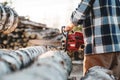 Close-up view on Professional strong lumberman wearing plaid shirt use chainsaw on sawmill Royalty Free Stock Photo