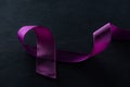 Close up view of purple ribbon on black background. Royalty Free Stock Photo