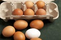 Close-up view of raw chicken eggs in grey box, egg white, brown egg on green background. Royalty Free Stock Photo