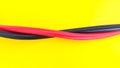 Close up of red and black electric cables isolated on yellow background Royalty Free Stock Photo