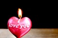 Close up view of red burning candle in the shape of heart on dark background. Royalty Free Stock Photo