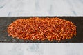 Close up view of red chili flakes on black slate background with selective focus. Crushed red cayenne pepper. Top view. Royalty Free Stock Photo