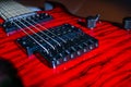 Close-up view of a red electric guitar with wood grain pattern, six strings, multiple control knobs and switches Glossy surface Royalty Free Stock Photo