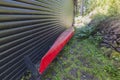 Close up view of red kayak parked near dark house wall.