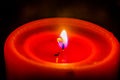 Close up View of a Red Single Thick Candle Burning on a Black Background. Calm Flame Burns at Night