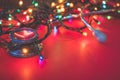 View of a red stethoscope lying on red background with colorful Christmas lights