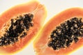 Close up view of ripe exotic papaya halves with black seeds isolated on white.