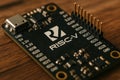 Close-up View of a RISC-V Microcontroller Board Showing Various Pins and Connectors on a Wooden Surface in a Well-Lit Royalty Free Stock Photo