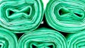 Close-up View of Rolled Green Disposable Plastic Trash Bags on White Background. Cleaning Supplies, Recycling Concept Royalty Free Stock Photo