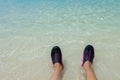 Close up view of rolling waves on men`s feet standing on white sand beach in swimming shoes. Curacao island. Royalty Free Stock Photo