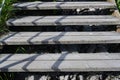 Close-up view of rough wooden steps over a rocky slope with a shadow strips