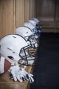 Close up view of a row of American football helmets sitting in a locker room before an football game. Gloves and a football also s Royalty Free Stock Photo