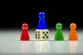 Close-up view of a row of colored figures and playing cube with blurred black and white background