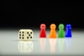 Close-up view of a row of colorful figures at the back with a playing cube on a blurred white-black background