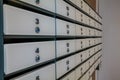 A close-up view of a row of white mailboxes with blue knobs. The mailboxes are organized in a neat, linear arrangement against a Royalty Free Stock Photo