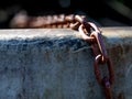 Close-up view of rusty old chain stretched over a concrete wall Royalty Free Stock Photo