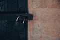 Close up view of a rusty padlock on weathered vintage wooden door with an old castle stone wall. Royalty Free Stock Photo
