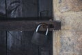 Close up view of a rusty padlock on weathered vintage wooden door with an old castle stone wall. Royalty Free Stock Photo