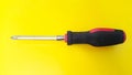 Close up of screwdriver with black and red handle isolated on yellow background Royalty Free Stock Photo