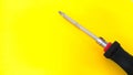 Close up of screwdriver with black and red handle isolated on yellow background Royalty Free Stock Photo