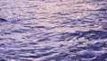 Close up view of sea waves on the tropical beach after sunset, purple surface of the water. Ocean water background