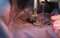 Close-up view of seamstresses`s hands sews to blue jacket leather inserts on sewing mashine.