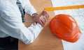 Close up view of senior businessman hands, hard hat and architect project on the table