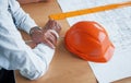 Close up view of senior businessman hands, hard hat and architect project on the table