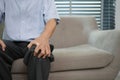 Close up view of senior grandfather suffering from knee pain sitting on sofa Royalty Free Stock Photo