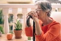 Close-up view of senior melancholy woman suffering from back pain sitting with her hands resting on the cane Royalty Free Stock Photo