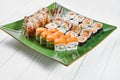 Close up view on set of assorted roll and sushi on green plate isolated on white wooden background. Sushi with salmon, eel. Royalty Free Stock Photo