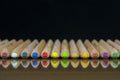 Close-up view of a set of colored pencils lying on a glass mat with reflection