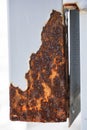 Close-up view of severe oxidation and rust on a white painted metal post, illustrating significant structural decay. Royalty Free Stock Photo