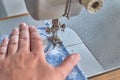 Close up view of sewing process. Female hands stitching blue fabric